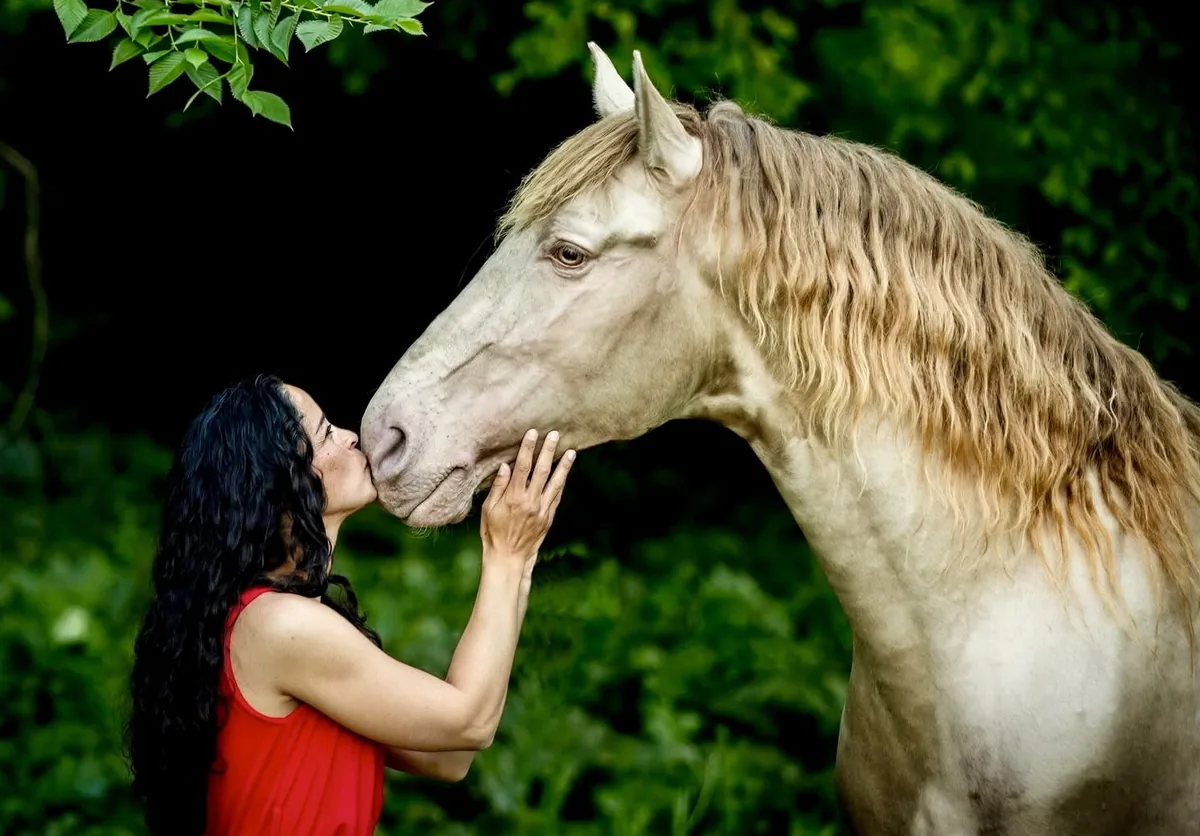 Angelina Zanker kissing the muzzle of a cremello stallion