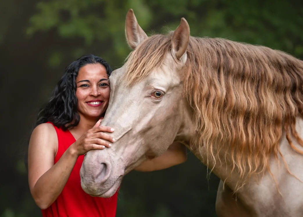 Angelina Zanker resting her head against the head of a cremello stallion